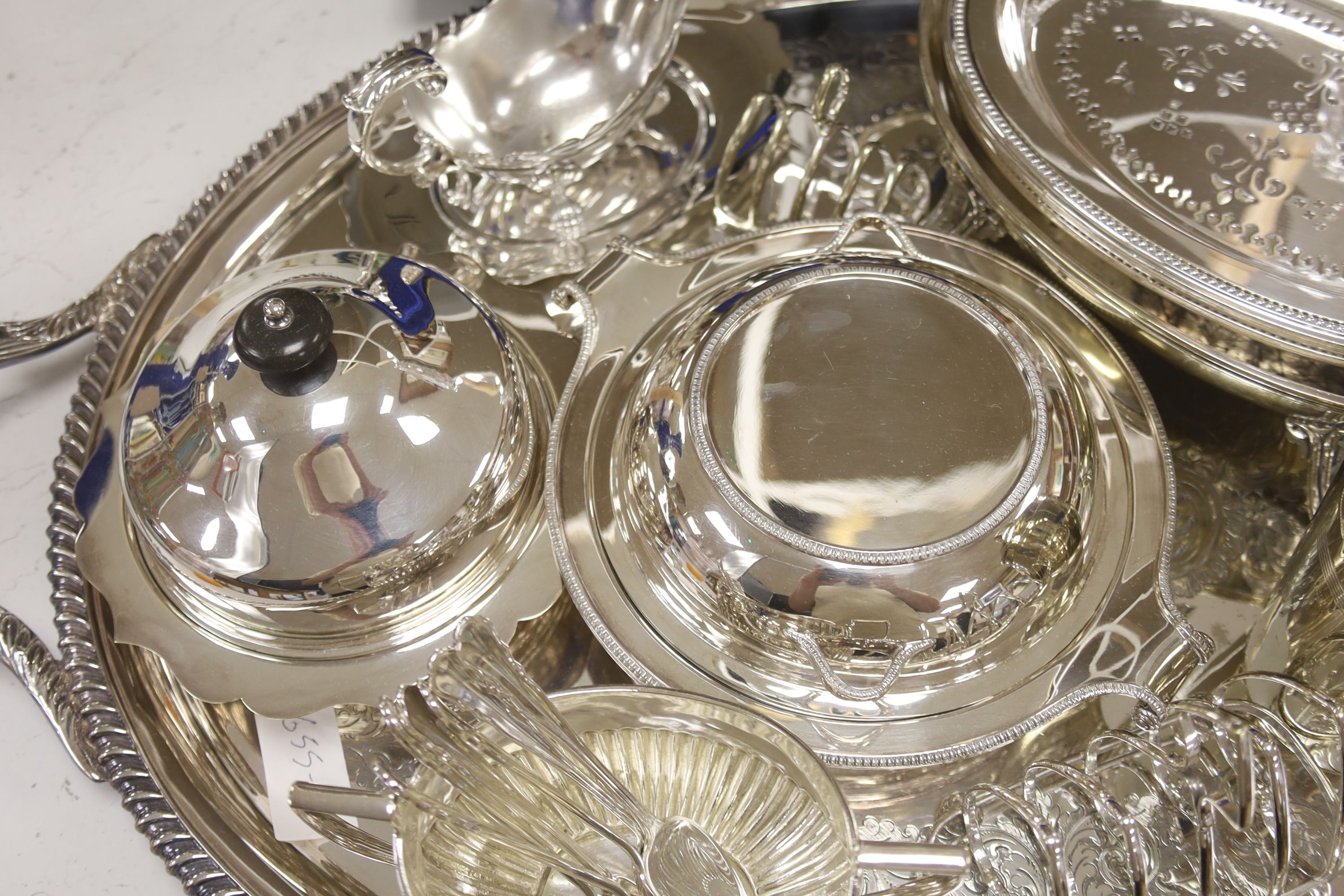 A collection of silver-plated wares to include an oval drinks tray, a cocktail shaker, serving tureens, etc.